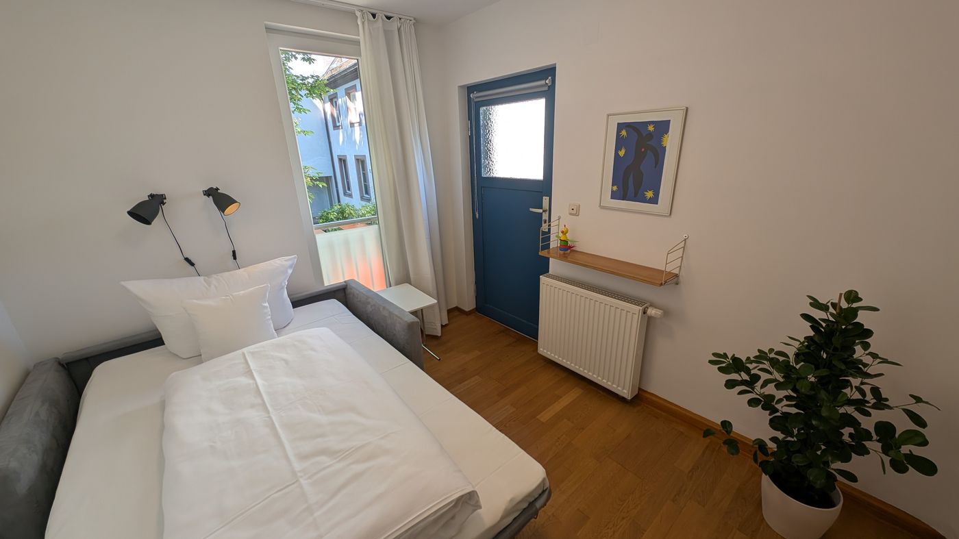 Kleines Schlafzimmer mit Bett und blauer Tür