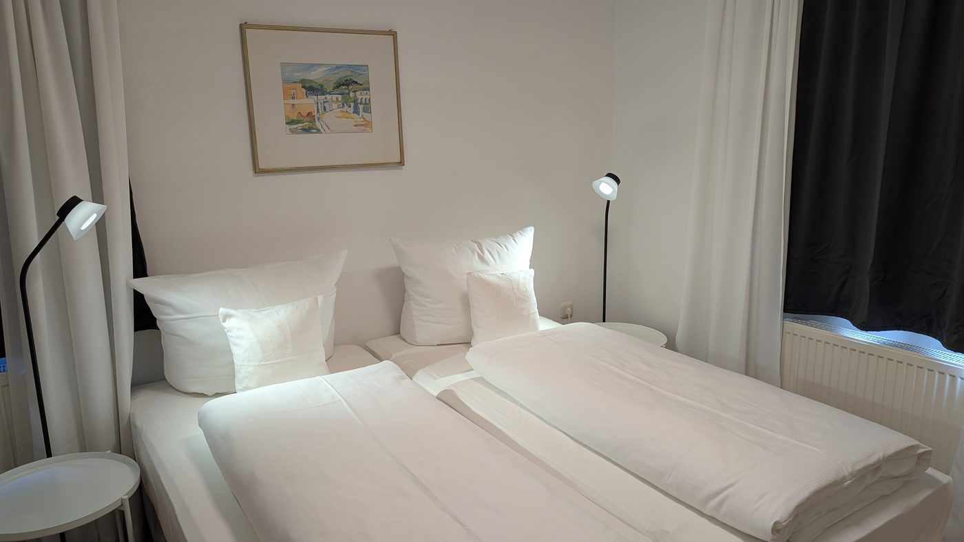 Doppelbett-Detail mit Leselampen und Kunstbild